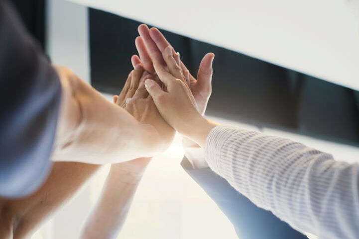 Menschen aus unterschiedlichen Berufsbereichen geben sich im Gebäude ein High Five